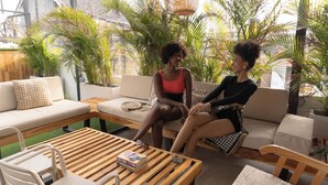 An indoor seating area with a sofa, a wooden coffee table, and a chair. There are potted plants around the room. - Casa Helena Hostel Cartagena (Cartagena)