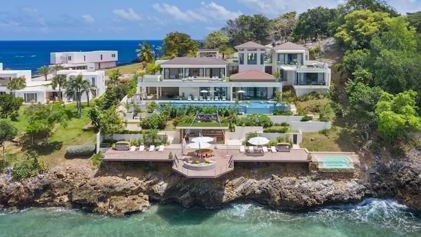 A coastal property with multiple buildings, a large swimming pool, and a rocky shoreline. - Gorgeous Beach House Perched Right Over the Ocean (Samaná)