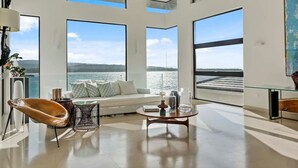 A spacious living area with large windows offering a view of the sea, a comfortable seating area, and a modern coffee table. - Gorgeous Beach House Perched Right Over the Ocean (Samaná)
