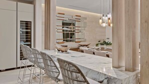 A modern kitchen with a marble island, white cabinetry, and pendant lighting. - Gorgeous Beach House Perched Right Over the Ocean (Samaná)