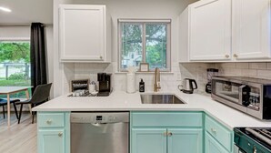 A modern kitchen with white cabinets, a dishwasher, a coffee maker, and a microwave. - Private Pool & Games - Pet-Friendly Fun Stay Mins to Downtown & Airport (Austin)