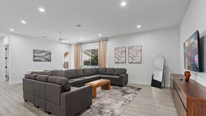 A modern living room with a sectional sofa, a coffee table, and a flat-screen TV. - Modern Austin Getaway & Near Downtown, Lake Travis & Event Venues! (Austin)