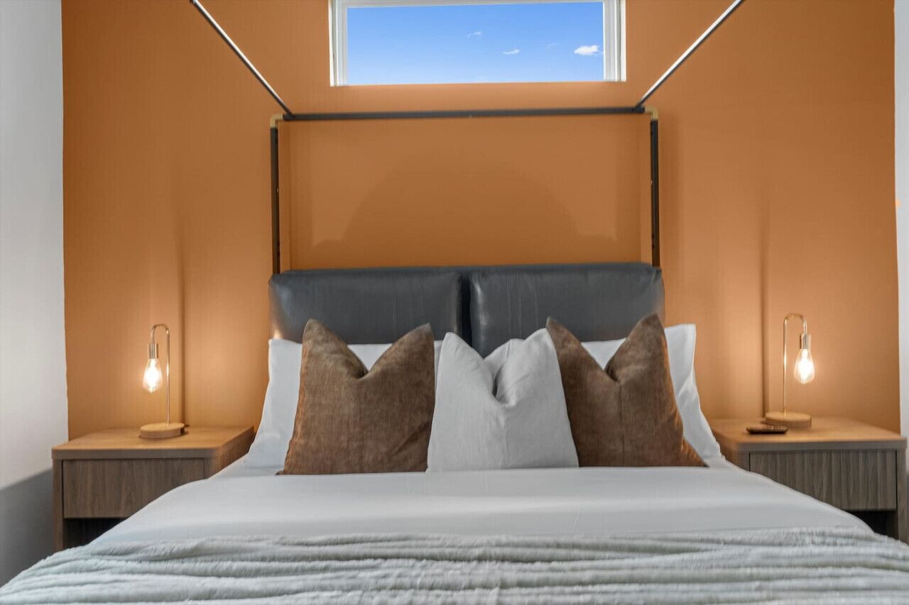 A modern bedroom with a skylight, a large bed with multiple pillows, and bedside lamps.