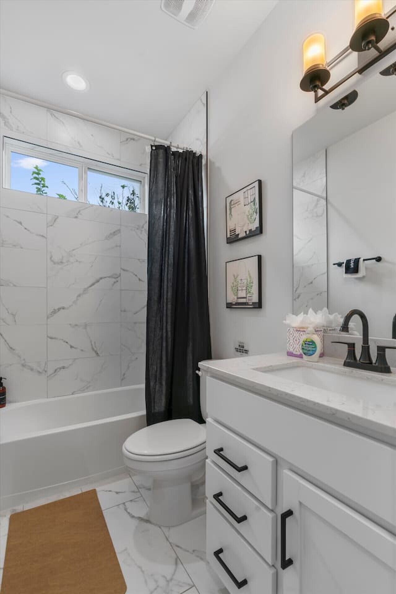 A bathroom with a bathtub, toilet, and vanity with a mirror.