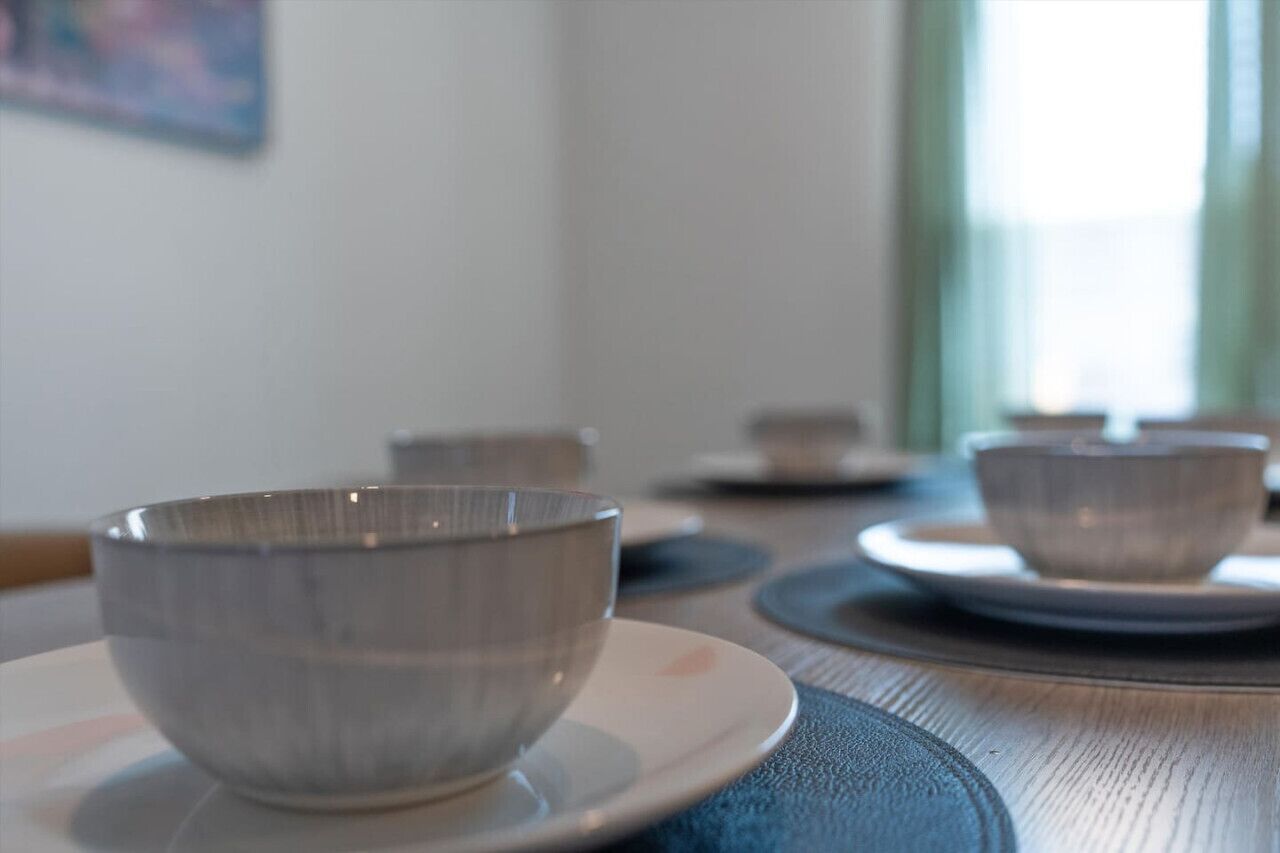 A dining table with a bowl and saucer in the foreground, and another bowl and saucer in the background.