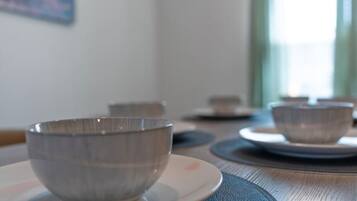 A dining table with a bowl and saucer in the foreground, and another bowl and saucer in the background.