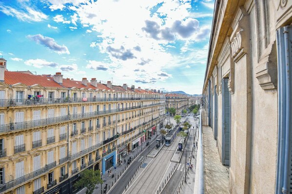 A row of historic buildings with balconies, a tram line, and a clear sky.