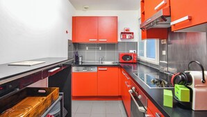 A compact kitchen with red cabinets, a microwave, and a sink.