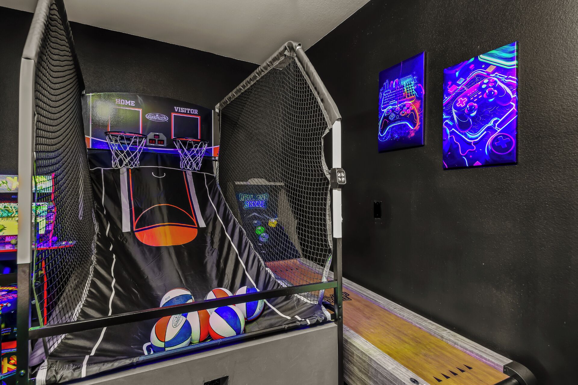 Ein Basketballplatz mit Netz, Anzeigetafel und zwei Neonkunstwerken an der Wand.