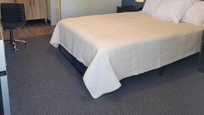 Et hotelværelse med seng, skrivebord, stol, natbord og et spejl.