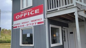 En toetages bygning med et skilt der siger 'Motel Office', en balkon og en lille indgang.