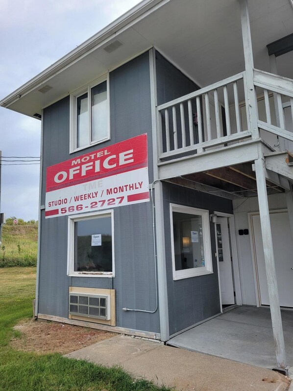 Ein zweistöckiges Gebäude mit einem Schild 'Motel Office', einem Balkon und einem kleinen Eingang.