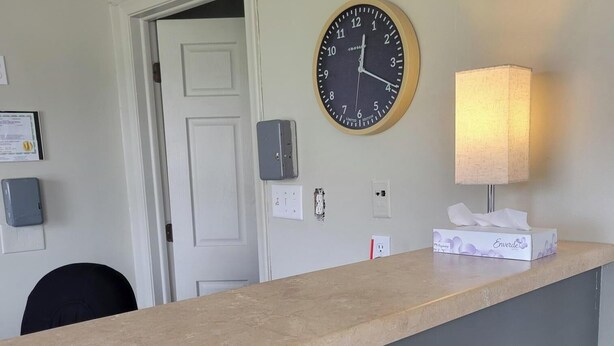 En receptionsdisk med et ur, en lampe og en servietkasse.