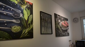 Een keuken met een magnetron, een klok en drie ingelijste botanische prints aan de muur.