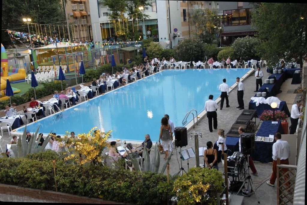 A large outdoor pool area with multiple seating arrangements and a stage for events.