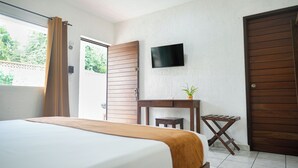 A hotel room with a bed, a desk, a TV, and a door.