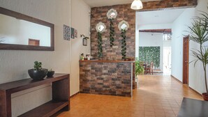 A reception area with a brick wall, a wooden console table with potted plants, a mirror, and a hanging light fixture.