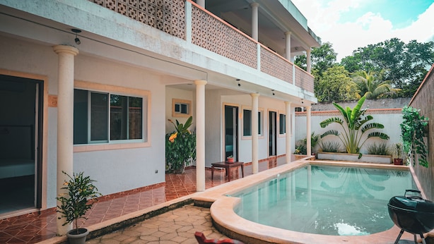 A residential building with a swimming pool, a covered patio, and a garden area with various plants.