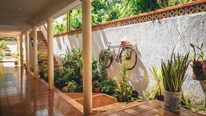 A covered corridor with tiled flooring, columns, and potted plants.