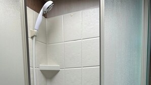 A shower with a handheld showerhead, a control panel, and a white tiled wall. - Cozy RV with 1 bedroom and WiFi, AC in fantastic Madison (Madison)