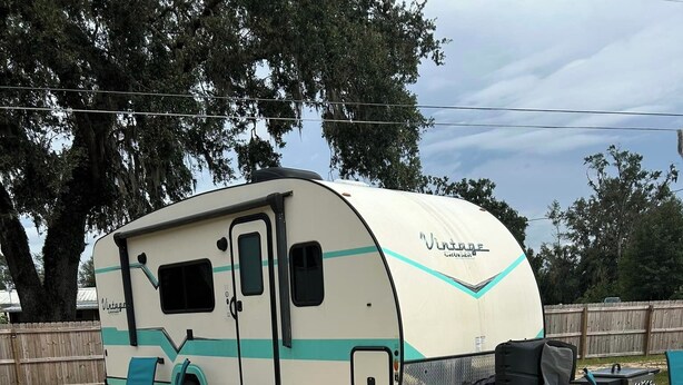 A recreational area with a picnic table, chairs, a grill, and a vintage camper parked in the background. - Cozy RV with 1 bedroom and WiFi, AC in fantastic Madison (Madison)