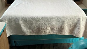 A single bed with a white quilt, wooden headboard, and matching nightstands. - Cozy RV with 1 bedroom and WiFi, AC in fantastic Madison (Madison)