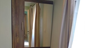 Une pièce avec une coiffeuse en bois, un miroir et une fenêtre avec des rideaux.