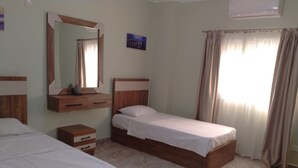 Une chambre à coucher avec deux lits en bois, une table de chevet, un miroir et une fenêtre avec des rideaux.