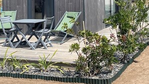 Un edificio moderno de madera con un patio que incluye una mesa y dos sillones.