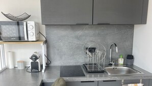 Una cocina moderna con microondas integrado, un lavamanos y un taburete de bar.