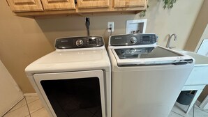 A compact laundry area with two stacked washers and a sink.