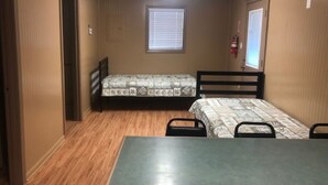 A small, single-room accommodation with two single beds, a table, and chairs.
