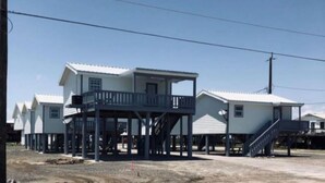 A row of two-story houses with a balcony on the ground floor, connected by a covered walkway.