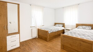 A bedroom with two wooden beds, a wardrobe, and a radiator. - Lux Suites Leipzig Luxury Apartment (Leipzig)