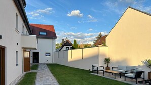 A modern house with a paved pathway leading to a patio area with outdoor furniture. - Lux Suites Leipzig Luxury Apartment (Leipzig)