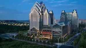 Een modern hotel met een opvallend architectuurontwerp, bestaande uit een centraal gebouw met een gebogen gevel en een bijgebouw met een puntig dak.