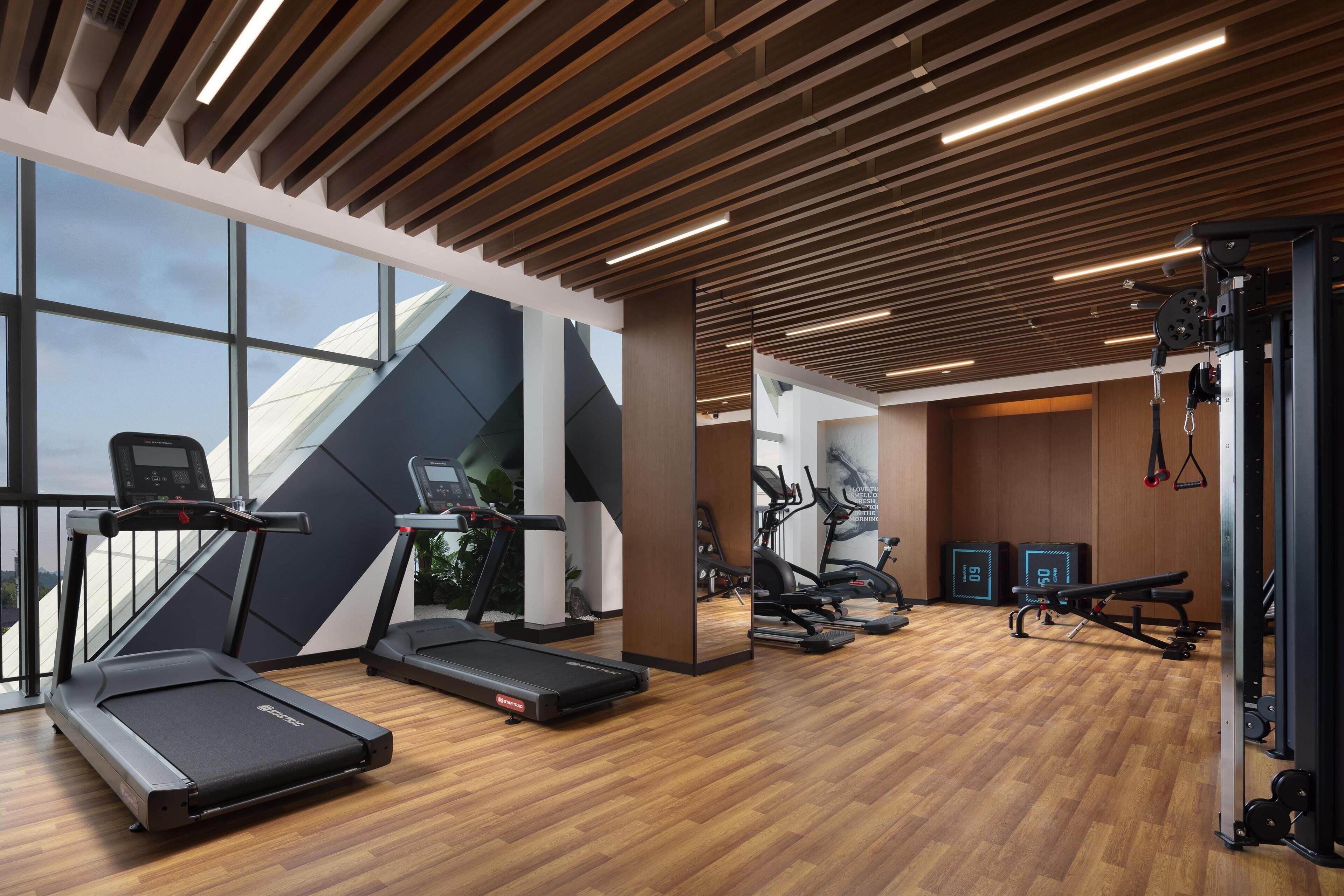 Un gimnasio moderno con cintas de correr, elípticas y equipamiento de levantamiento de pesas.