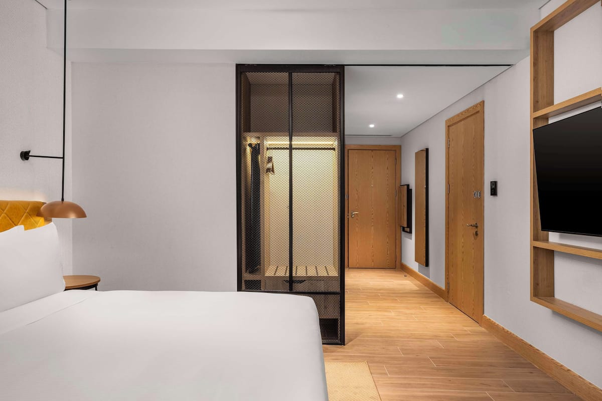 Habitación de hotel moderna con una cama grande, un escritorio, un armario y un televisor.