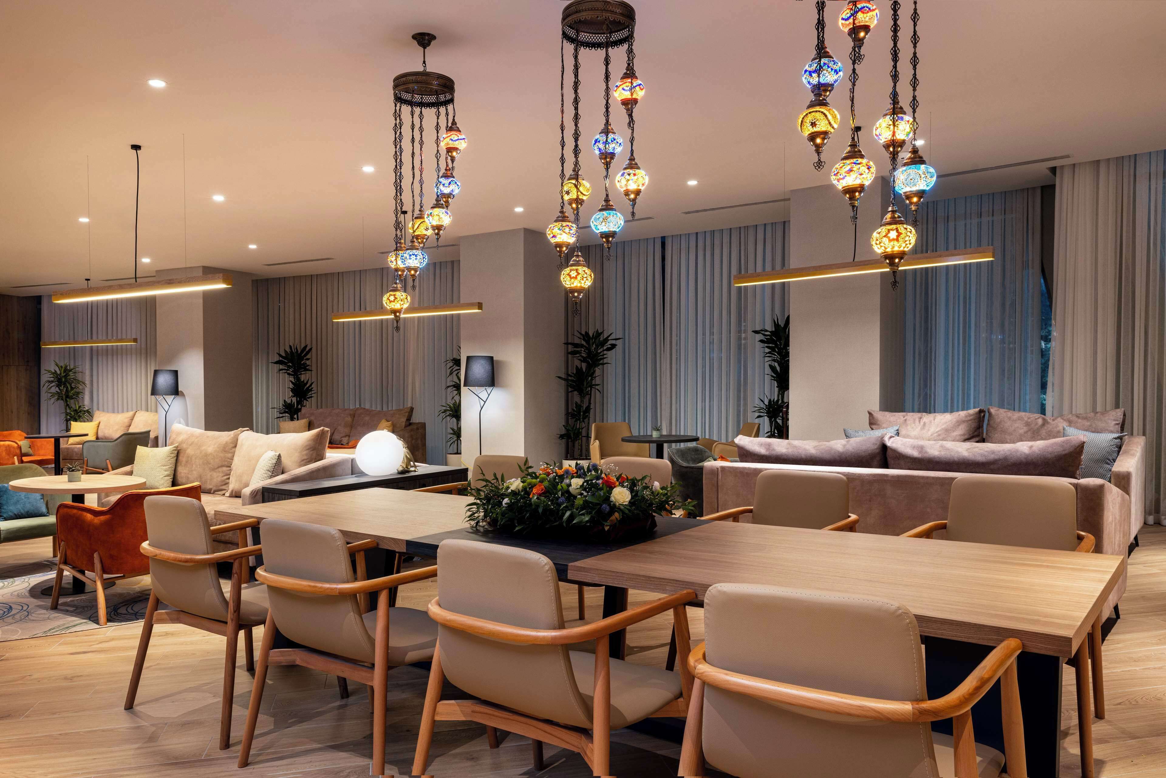 Un salon moderne avec une table à manger en bois, des canapés de couleur beige et des luminaires décoratifs suspendus.