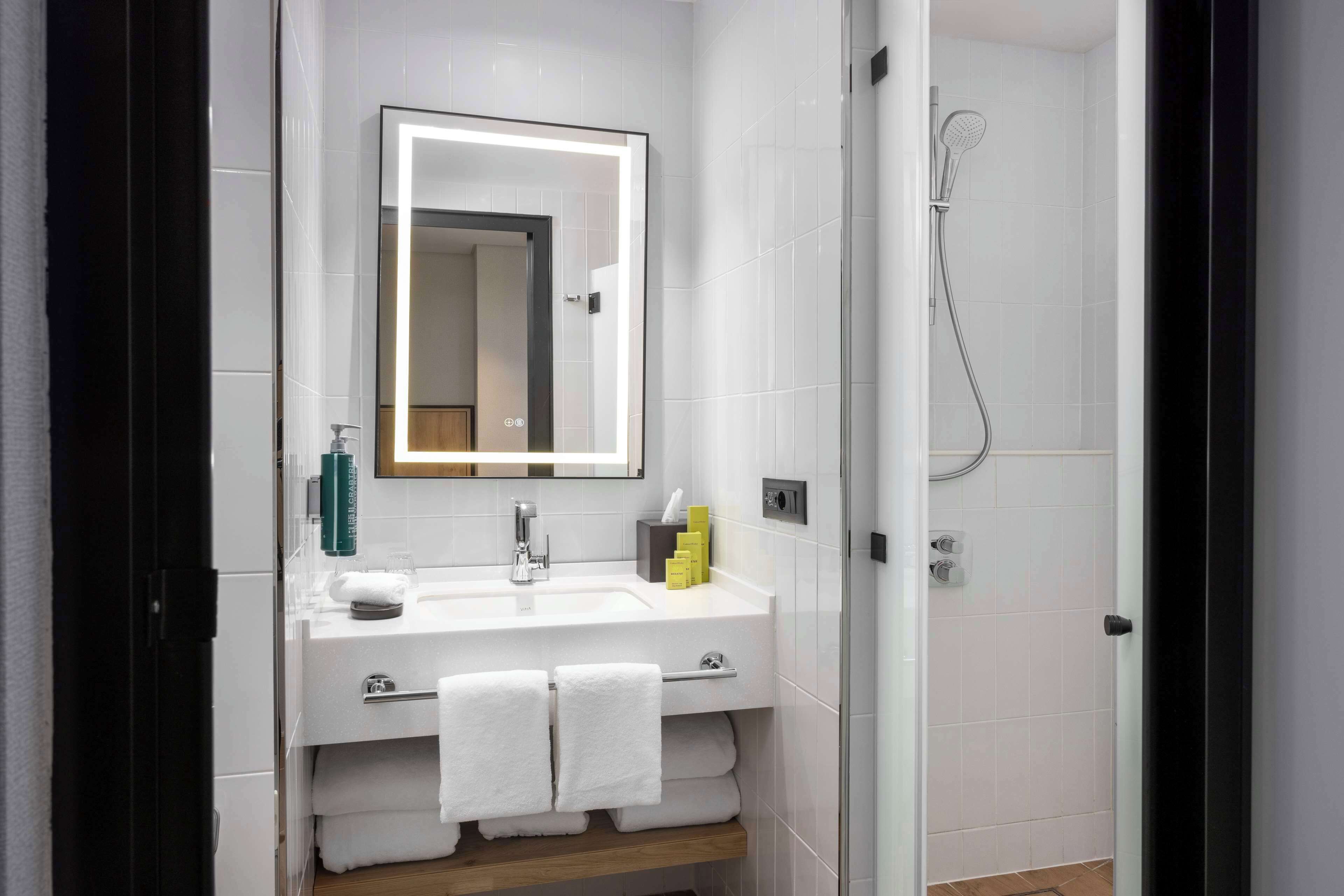 A modern bathroom with a white sink, mirror, and shower.