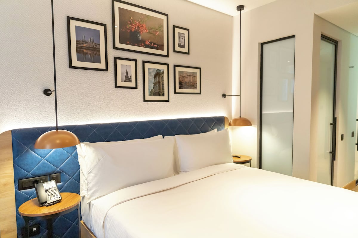 Una habitación de hotel con una cama, un teléfono y cuadros en la pared.