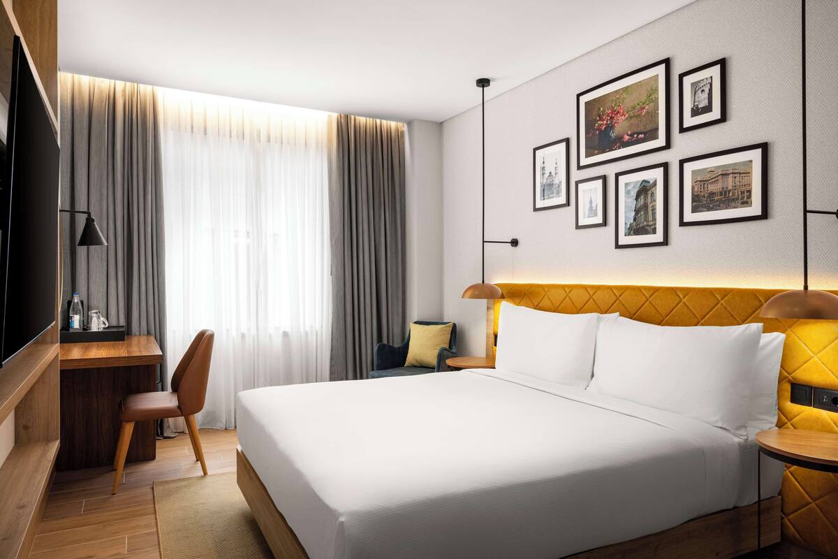 Una habitación de hotel con una cama grande, un escritorio, una silla y un televisor.