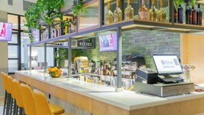 Un espace bar moderne avec un long comptoir, des chaises jaunes et des étagères remplies de bouteilles.