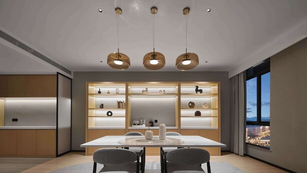 Un espace repas moderne avec une table blanche, deux chaises grises et des luminaires suspendus.