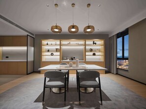 Un comedor moderno con una mesa blanca, dos sillas grises e iluminación colgante.