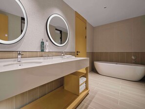 Un baño moderno con tocador doble lavamanos, dos espejos fijos en la pared, un estante de madera con toallas y una bañera independiente.