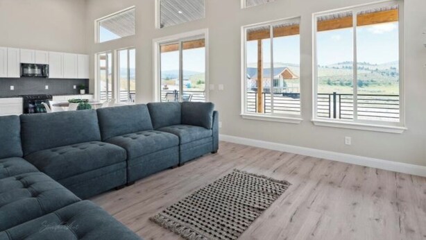 A spacious living room with a sectional sofa, large windows, and a view of the outdoors. - Modern 2024 build, in welcoming Lava Hot Springs. Top unit. (Lava Hot Springs)