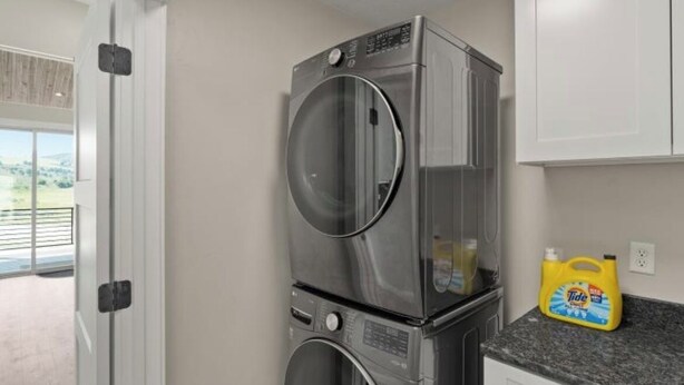 A compact kitchen with a stacked washer and dryer, a granite countertop, and a view through an open door. - Modern 2024 build, in welcoming Lava Hot Springs. Top unit. (Lava Hot Springs)