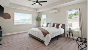 A bedroom with a bed, ceiling fan, large windows, and a view of the outdoors. - Modern 2024 build, in welcoming Lava Hot Springs. Top unit. (Lava Hot Springs)
