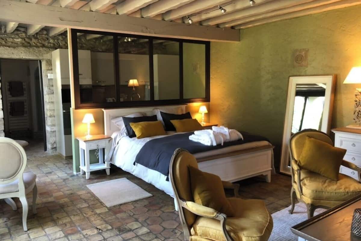 A bedroom with a bed, two bedside lamps, a chair, a table, and a mirror.